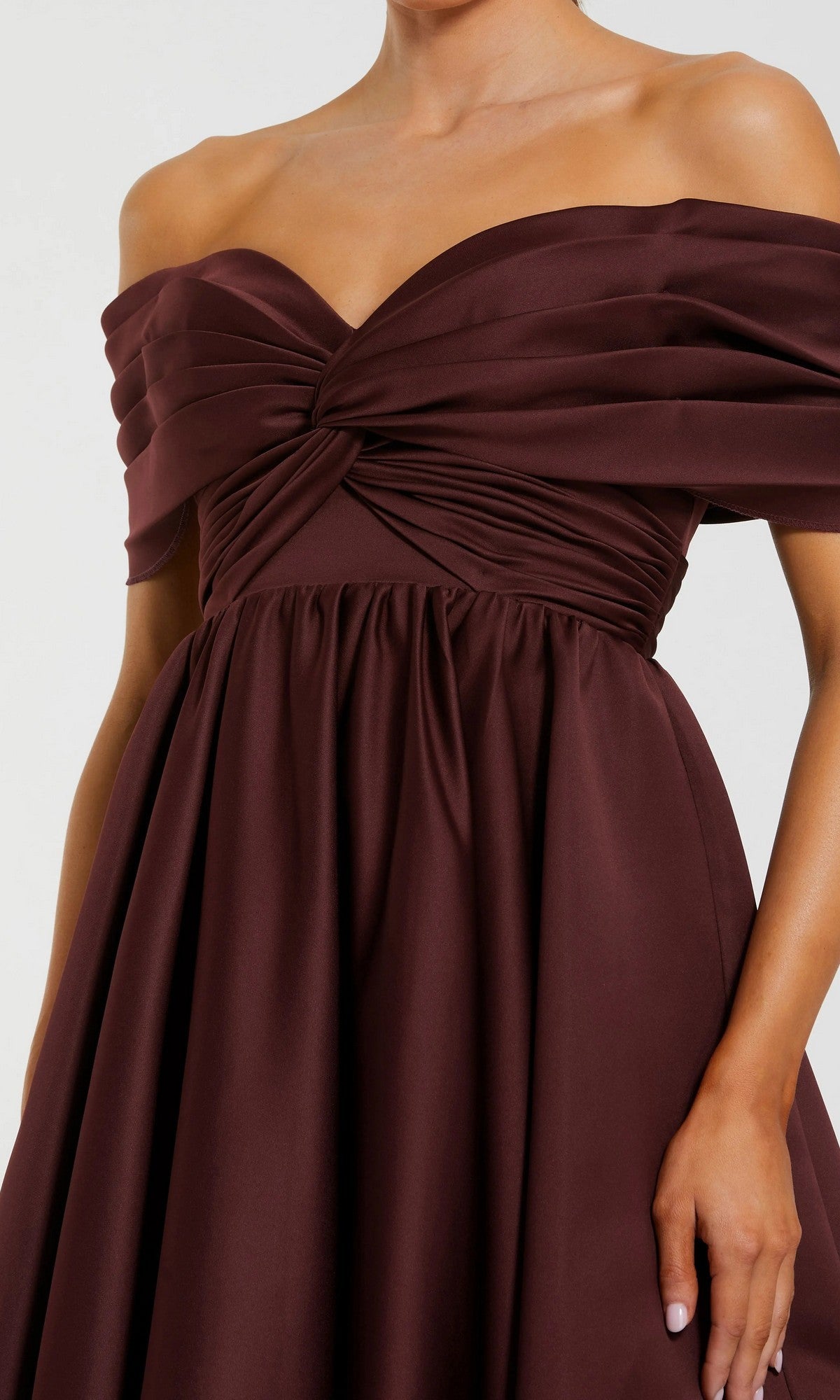 A woman wears the Mac Duggal 56188 Long Formal Dress in dark burgundy, featuring an off-the-shoulder neckline, twisted ruched bodice, and gathered skirt.